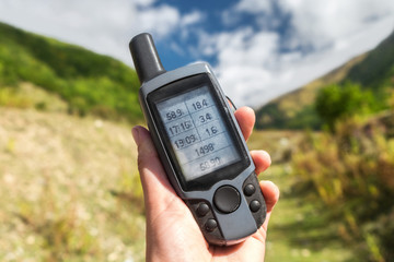 Old GPS navigator in hand on a nature background