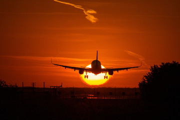 Fototapeta na wymiar Silhouette of an air plane over the sun with beautiful red clouds in background