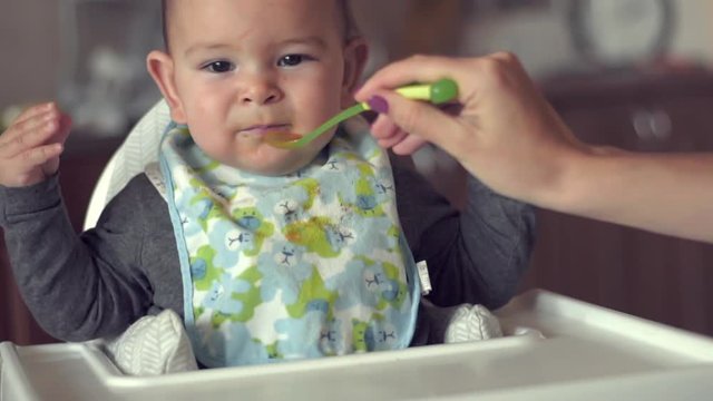 Mom give spoon baby child infant in high chair kitchen weaning solids independent toddler