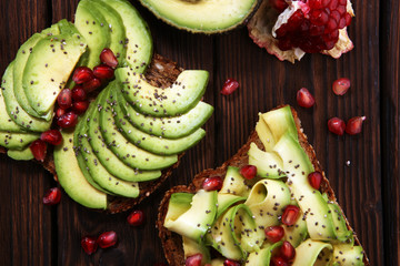 sliced avocado and ripe pomegranates on toast bread with spices and avocado.