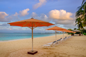 Parasols and sun loungers facing the Caribbean Sea on Seven Mile Beach, Grand Cayman, Cayman Islands