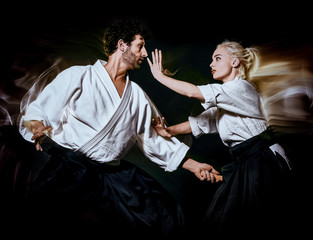 two bodokas fighters man and woman practicing Aikido studio shot isolated on black background - obrazy, fototapety, plakaty