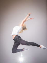 Young slim gymnast in gracefull jump studio shot