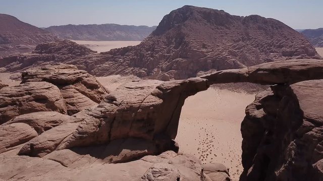 Drone flying over natural arch stone bridge in desert