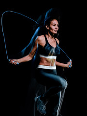 one beautiful caucasian mixed race woman exercising  jumping rope fitness exercises in studio isolated on black background