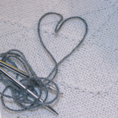 heart lined with thread for knitting on the background of a white jacket hand-knitted