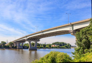 Concrete bridge spanning over the Illinois River by Peoria, showing the shoreline and sky.