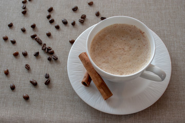Cappuccino white cup with cinnamon sticks.