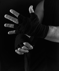 Fototapeta na wymiar man wraps his hands in black textile bandage for sports
