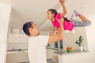 Happy family. Young father playing silly with his daughter lifting her up
