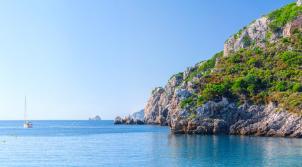 Beautiful summer panoramic seascape. View of the cliff into the sea bay with crystal clear azure water in sunshine daylight. Boats and yachts in the harbor. Mediterranean sea, somewhere in Europe.