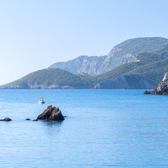 Beautiful summer panoramic seascape. View of the cliff into the sea bay with crystal clear azure water in sunshine daylight. Boats and yachts in the harbor. Mediterranean sea, somewhere in Europe.