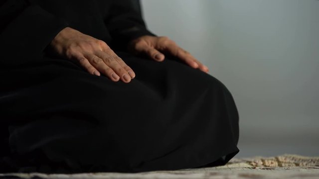 Woman in traditional black hijab kneeling on prayer mat mosque, islamic culture