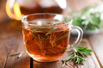 Rosemary tea in glass tea cup on rustic wooden table closeup. Herbal vitamin tea.