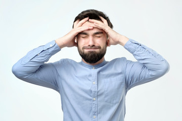 Young unhappy businessman holds his head, stress, headache and frustration concept