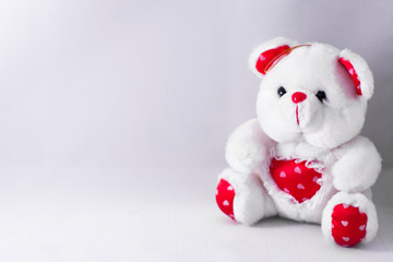 White Teddy Bear with red heart sitting on white background. Toys for children concept. Valentine's day background. Gift for woman or child.
