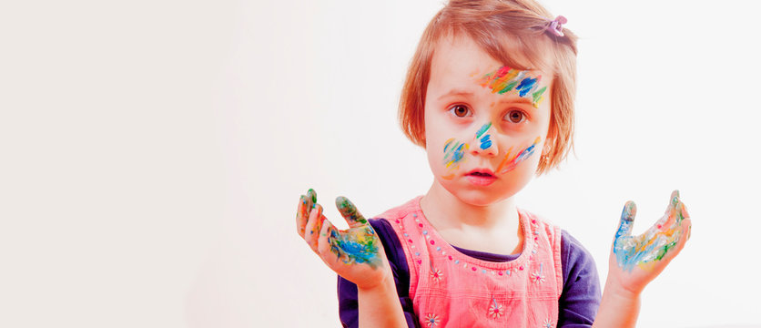Portrait of little cute girl with children's makeup and painting colorful hands.