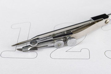 Fototapeta premium A companion for drawing circles on a white piece of paper. Drafting accessories for drawing technical drawings.