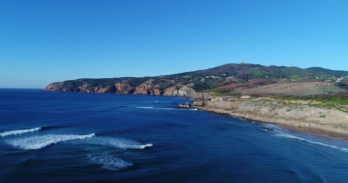 Aerial view of coastline near the Guincho Beach (Praia do Guincho) with the Roca Cape (Cabo da Roca) on the background; Concept for travel in Portugal and visit Cascais
