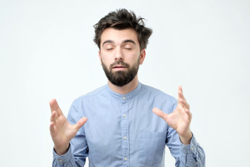 Naklejka premium Unsatisfied sleepy guy with messy hair standing over gray background.