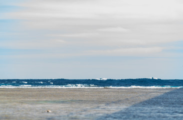 Sandy tropical beach with blue ocean and waves