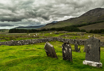 Old Graveyard With Weathered Tombstones In Highland Landscape With Sheep On The Isle Of Skye In Scotland