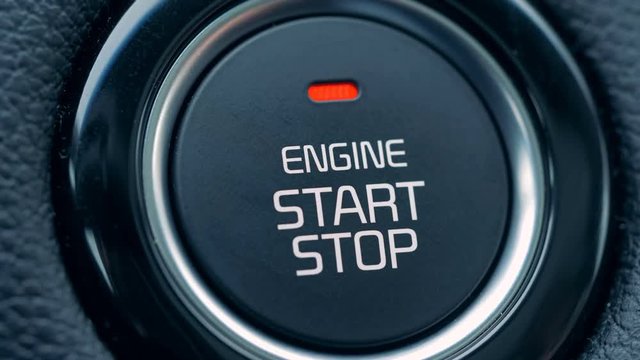 A driver starts a car, pressing a button, close up.