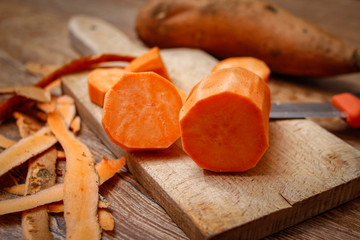 Fototapeta na wymiar Raw sweet potato whole and chopped on old kitchen cutting table. 