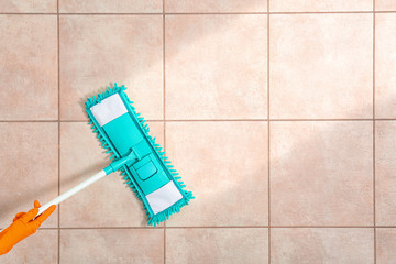 Woman cleaning tile floor with mop, top view. Space for text