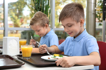 Cute children at table with healthy food in school canteen