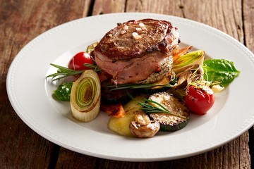 Leg of lamb steak wrapped in bacon with grilled vegetables