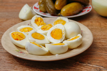 Hard boiled chicken eggs in a porcelain plate on vintage wooden table