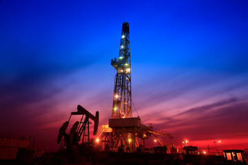 The pumping unit is at work in the evening of the oilfield - obrazy, fototapety, plakaty