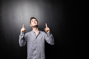 Portrait of excited man in checkered shirt pointing fingers up over white background