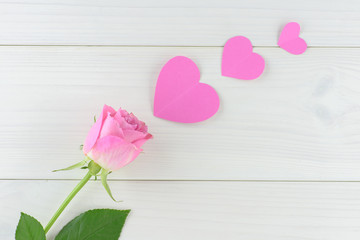 Pink roses and hearts on a white wooden table, Valentine day background, top view.