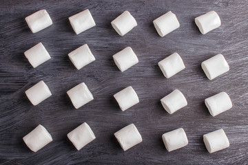 set of marshmallows on black wooden background. geometric pattern.