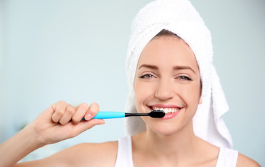 Portrait of young woman with toothbrush on blurred background
