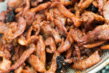 Deep Fried small pieces of Pork Beef in bulk in boiled oil pan for sale as street food by road vendor,  Meat is tender and crispy, famous food with sticky rice for local people, selective focus