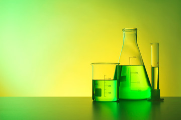 Chemistry laboratory glassware with samples on table against color background