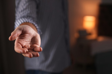 Fototapeta premium Man offering helping hand on blurred background, closeup. Space for text