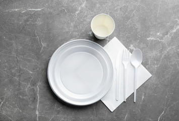 Composition with plastic dishware on grey background, flat lay. Picnic table setting