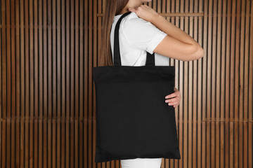 Woman with eco bag on wooden background. Mock up for design