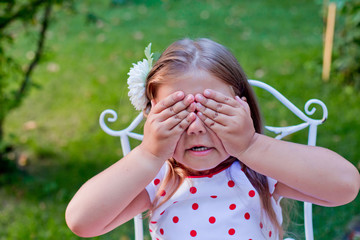 Little beautiful girl covered eyes hands