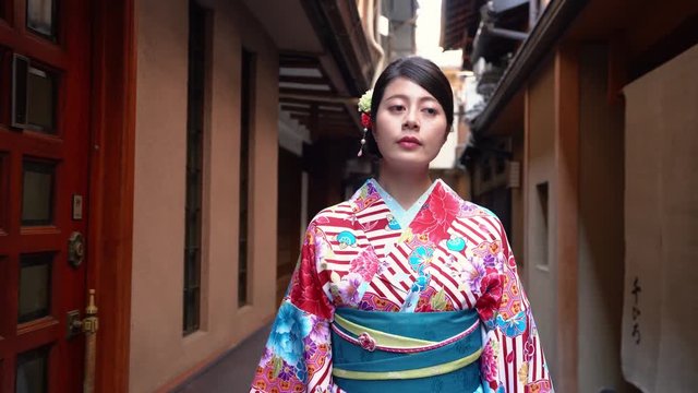 elegant beautiful kimono dressing traveler girl walking along in little path in japan. young japanese lady wearing traditional costume seeing around in hanamikoji dori in kyoto japan.