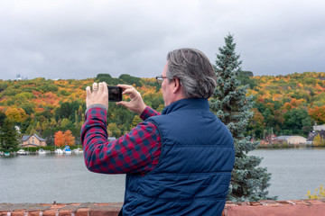 Man taking photo of fall colors on smartphone