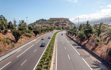 Fototapeta na wymiar LA OROTAVA TENERIFE SPAIN - JUNE 2014 Highway north of Tenerife with cars driving on a sunny day
