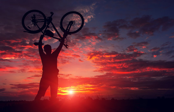 tourist with a bicycle on the background of a fiery sunset