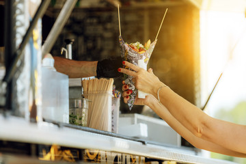Close-up of woman's hand receiving food in a food truck