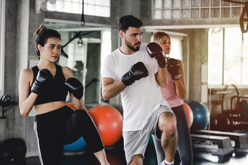 Sporty woman and men with the back boxing gloves training at the gym