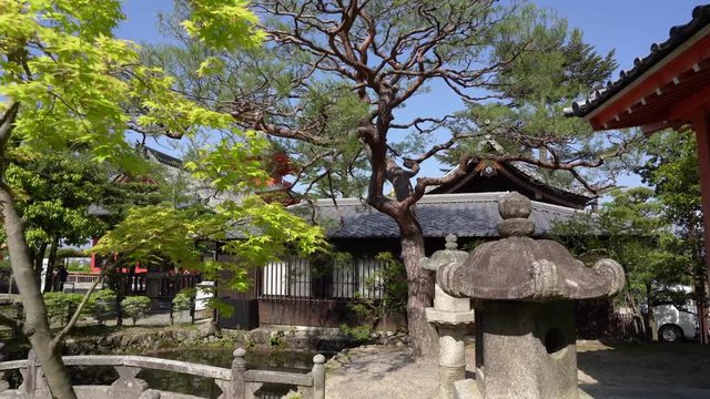 traditional wooden japanese style house with pond trees stone lanterns toro in spring. many tourists visiting kiyomizu dera temple in kyoto japan in background. beautiful sunny day in asia.